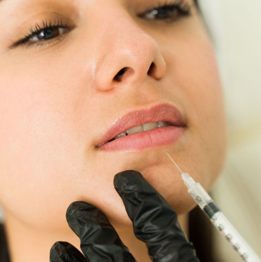 Close-up image of a cosmetologist administering botulinum toxin as filler treatment for beauty enhancement in a clinical setting