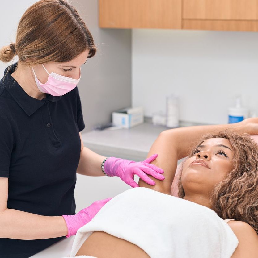 Dermatologist doctor consulting a young woman on the problem of hyperhidrosis in a modern clinic of aesthetic medicine