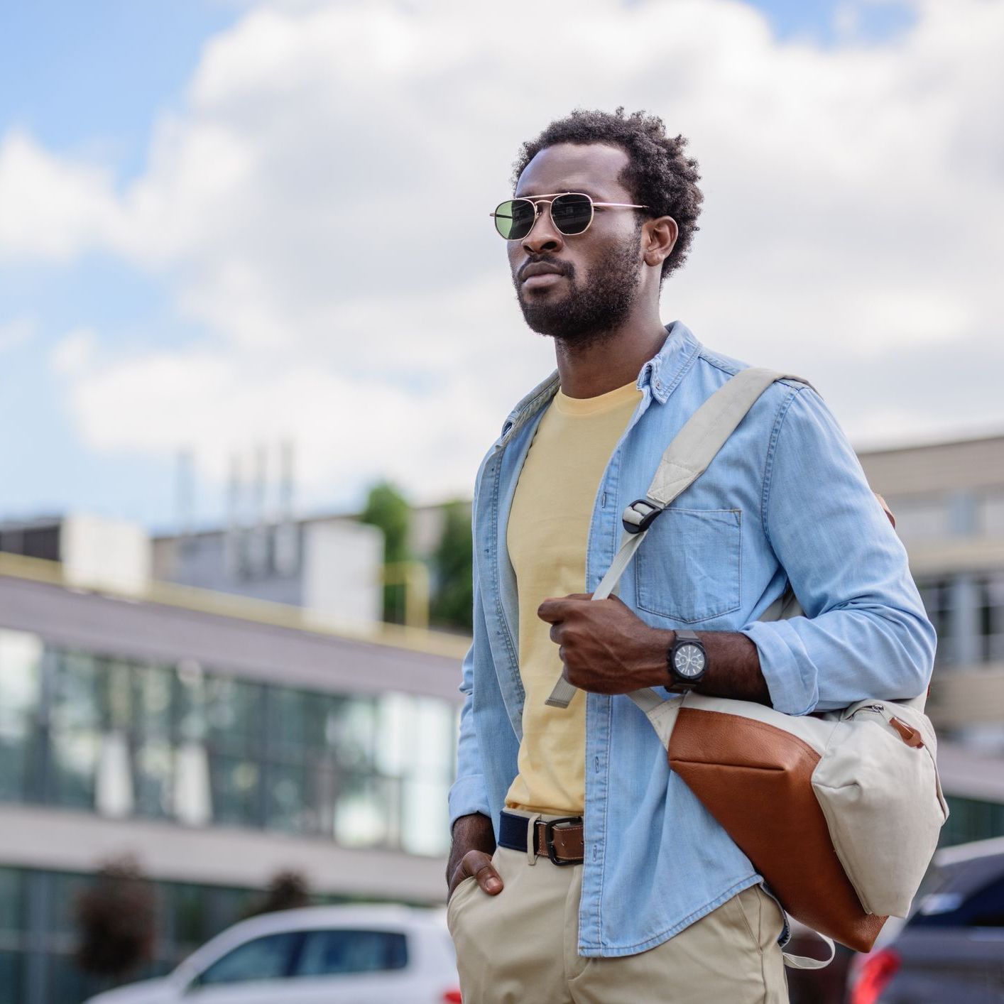 confident african american man looking away while holding hand in pocket