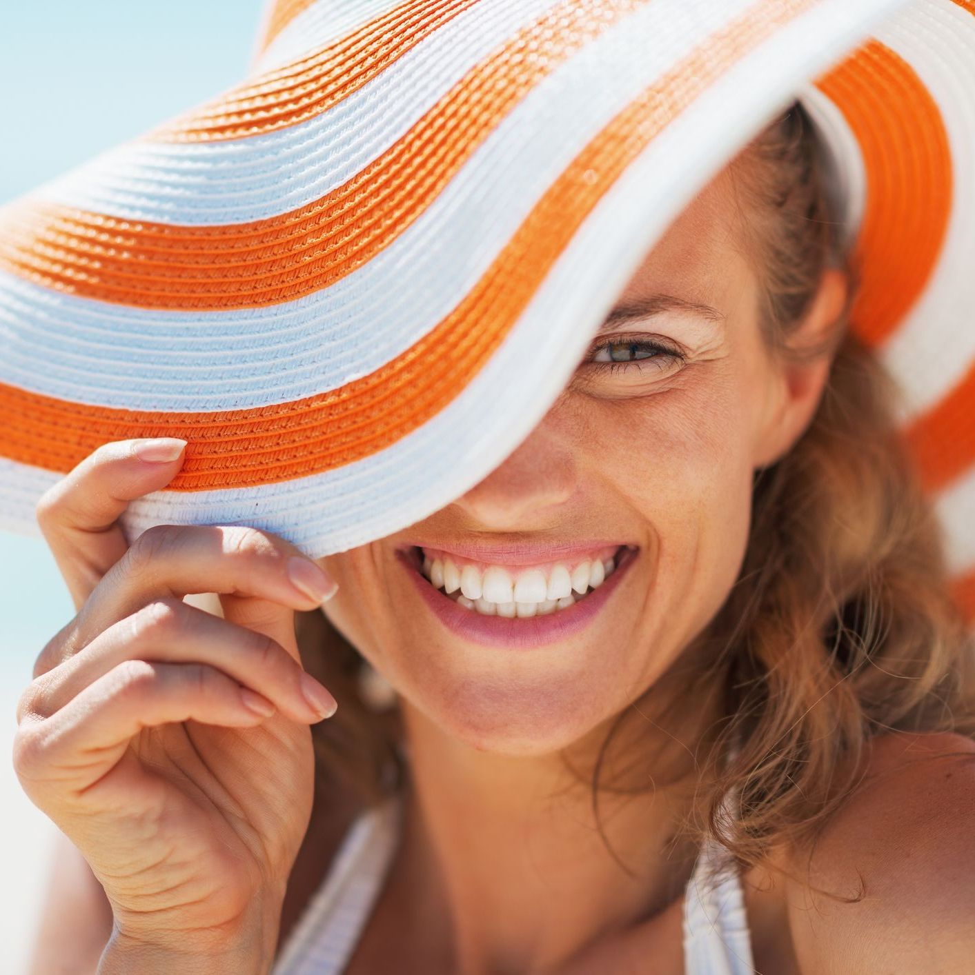 Portrait of happy young woman in swimsuit and beach hat
