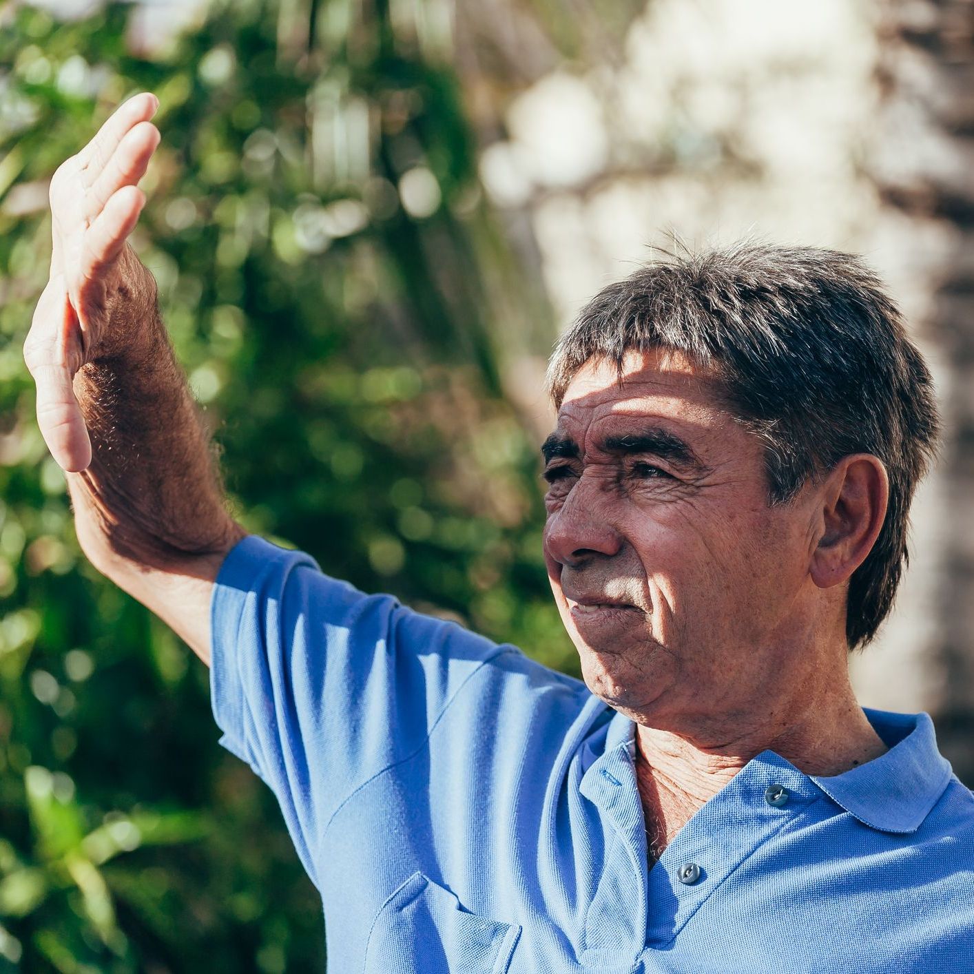 Mature man covering face by hand of bright sun light